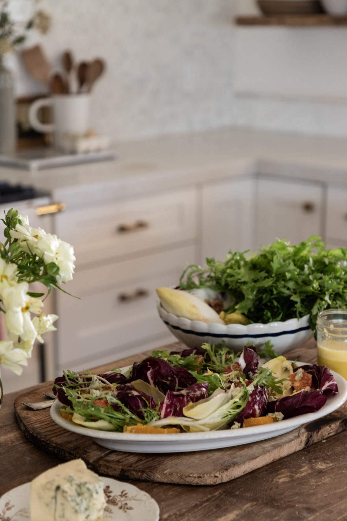 A vibrant endive salad presented on a white plate, featuring crisp Belgian endive and radicchio leaves arranged in a circular pattern. The salad is topped with bright orange slices, crumbled blue cheese, and crunchy walnuts. Fresh parsley adds a touch of green, creating a beautiful and appetizing dish perfect for any gathering.