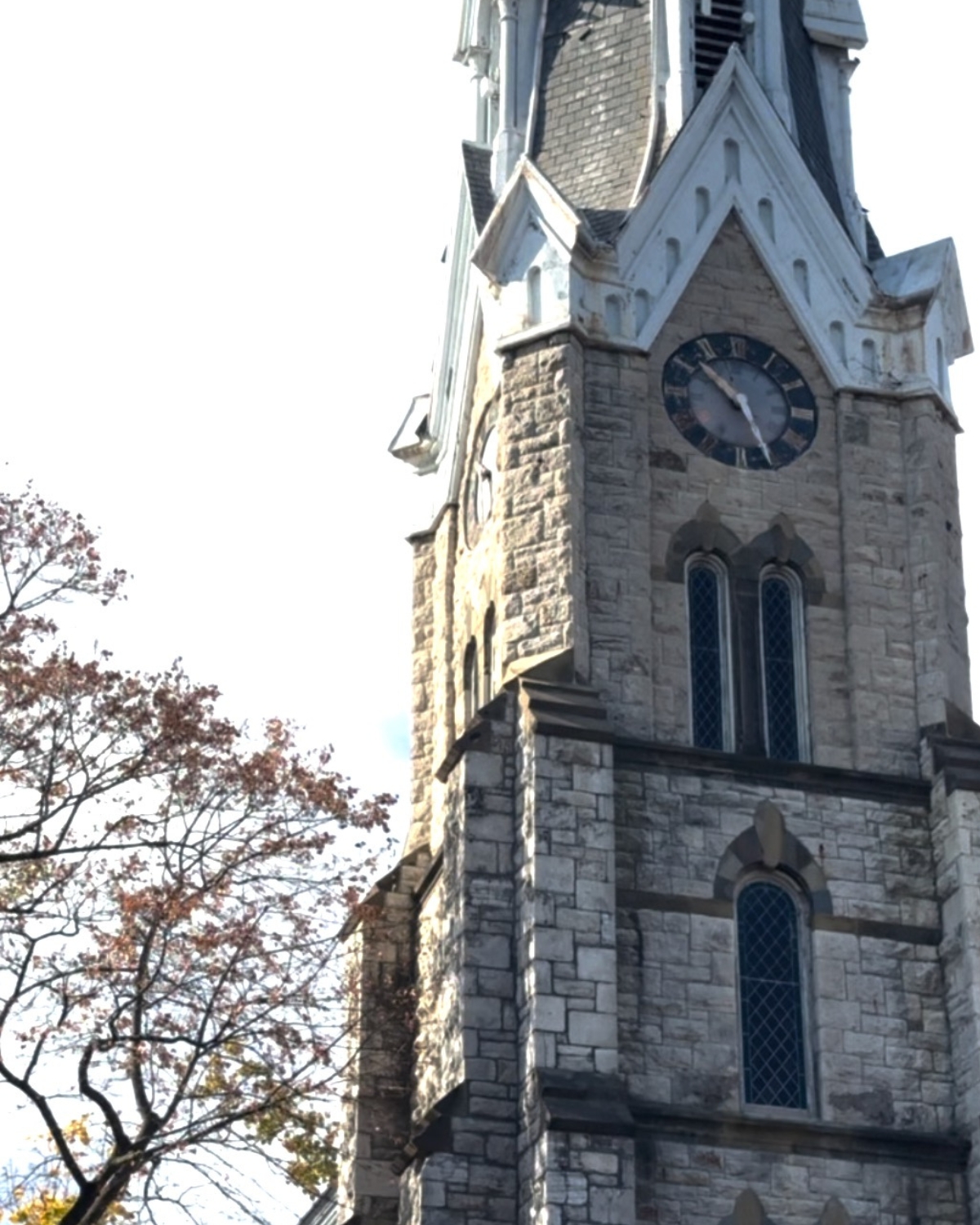 Stunning church tower with a classic clock, towering over the surrounding landscape and showcasing beautiful architectural details against a clear sky.