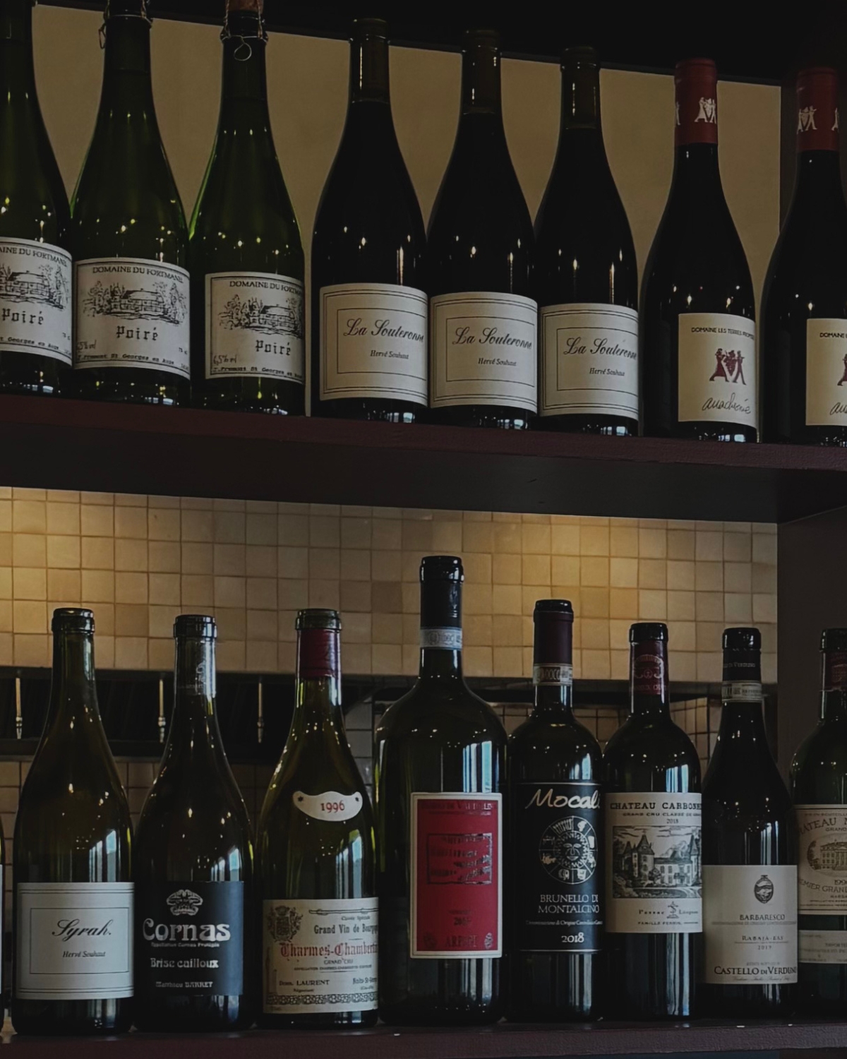 Close-up of a glass of wine at the bar, set against the elegant backdrop of a Jenni Kayne-designed space, highlighting the warm ambiance and stylish details of the setting.